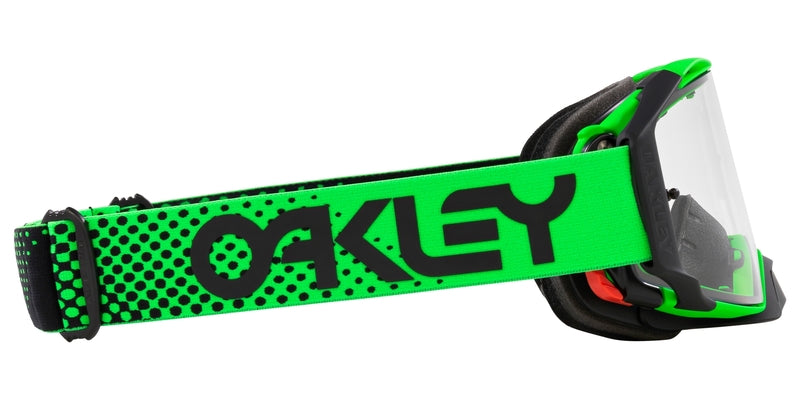 OAKLEY Airbrake MX-Brille in Grün mit klarem Glas, für Motocross, sitzt auf einem Kopf mit Helm, Detailansicht der Brille.