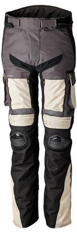 Robuste RST Ranger CE Motorradhose für Herren in Sand und Graphit, mit Schutz- und Adventure-Design, auf einem Motorrad liegend.