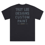 Schwarzes Troy Lee Designs Paint Shop T-Shirt, Freizeitbekleidung, weiches Baumwollmaterial, liegt flach auf einem weißen Hintergrund.
