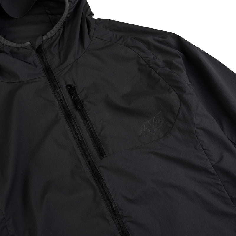Troy Lee Designs Drift Windbreaker Mono Carbone, schwarze Freizeitjacke mit Markenlogo, winddicht und sportlich, vorne sichtbar.