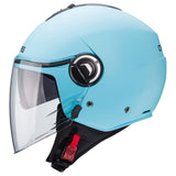 Mann trägt eine matte hellblaue Caberg Riviera V4 X Jethelm, Blick von vorne, mit Visier und aerodynamischem Design.