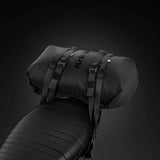 Schwarzer Kriega Rollpack-20 mit robustem Design, sichtbar auf einer Motorradtasche, ideal für Gepäck- und Campingausrüstung.