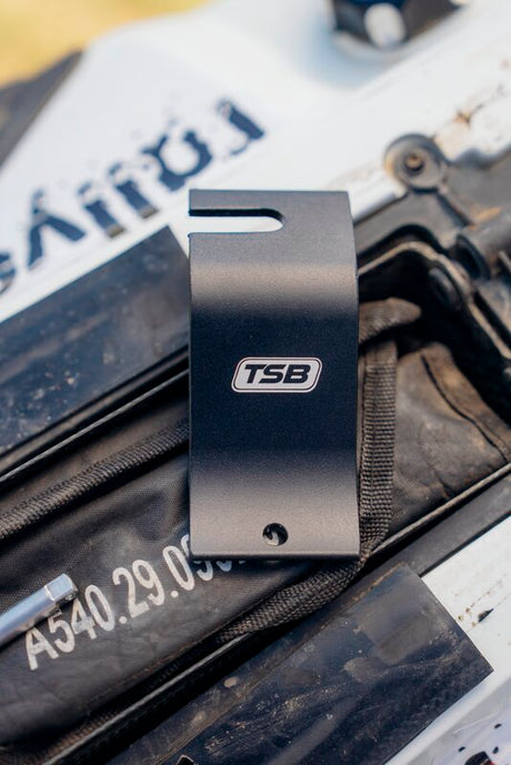 Schwarz TSB-RACING Reifenmontagehilfe, Werkzeug zum sicheren Halten und Montieren von Reifen, auf dem Reifenhalter liegend.